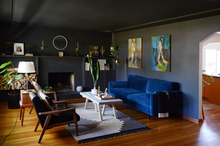 现代客厅，黑色的墙壁和天花板，蓝色的天鹅绒沙发