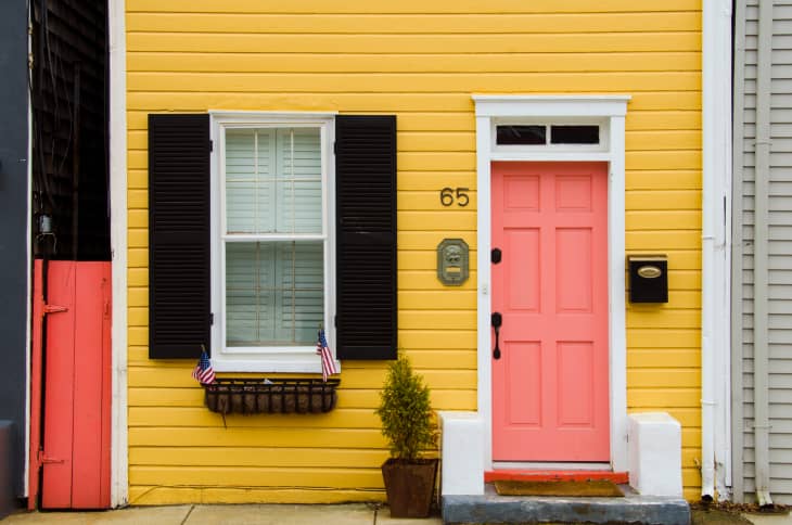 Yellow house facade with pink door, shutters, and address number