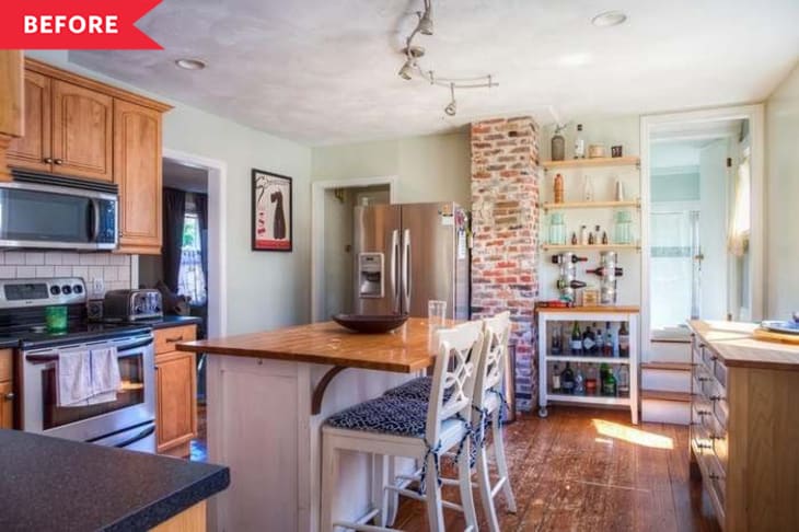 Kitchen with wooden cabinets, stainless steel appliances, brick accent wall, and island with two white chairs.