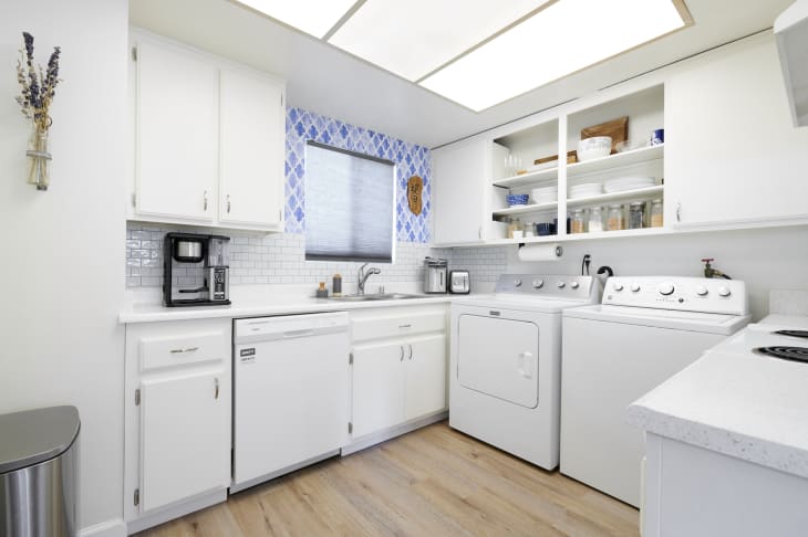 A white kitchen with a washer and dryer in the room