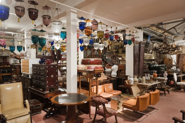 photo of antique and vintage furniture store interior. Lots of different tables, dressers, chairs, etc. Hanging different-colored pendant lights for sale