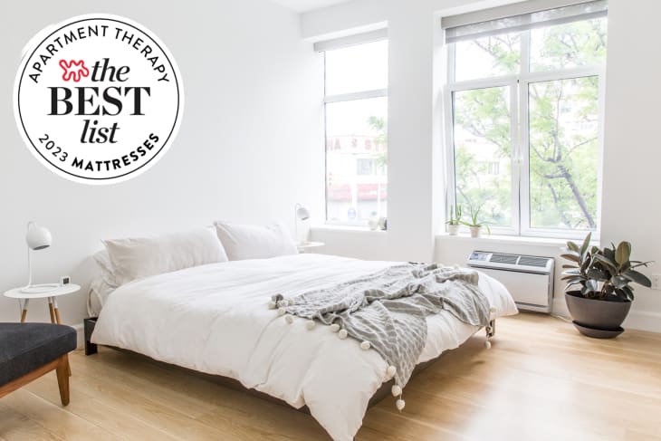 White minimal bedroom with platform bed with white bedding. Seal in upper left reads: "Apartment Therapy the Best List 2023 Mattresses"
