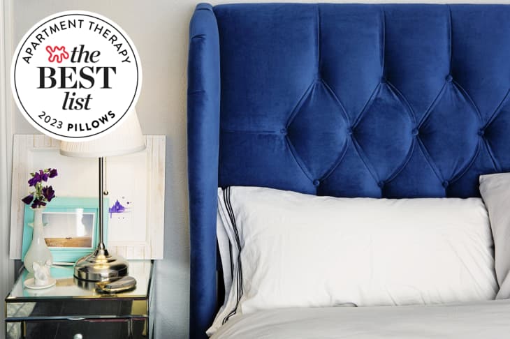 Bed with blue tufted headboard and fluffy white pillows. Seal in upper left corner reads "Apartment Therapy the Best List 2023 Pillows"