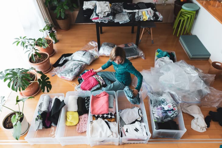 a woman organizes clothes in living room of her home.