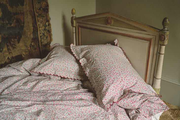 Floral-patterned bedding with scalloped edges on a vintage wooden bed.