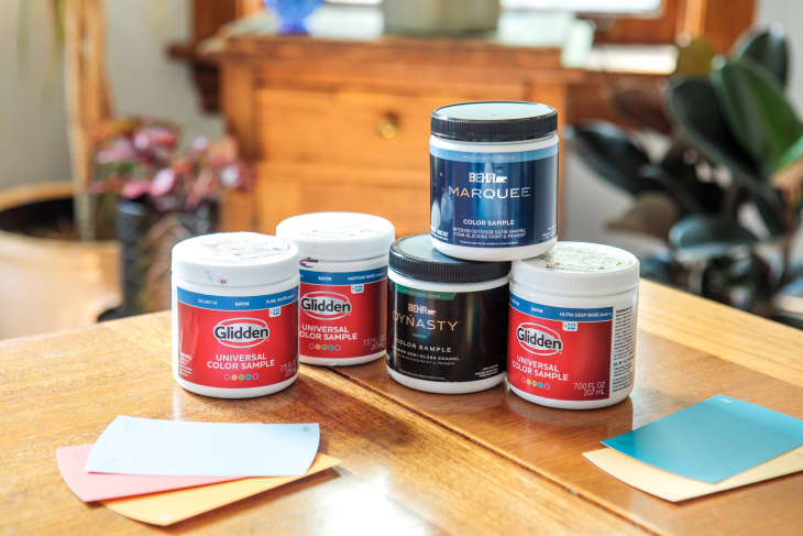 various paint sample pots sitting on a table with some paper paint swatches