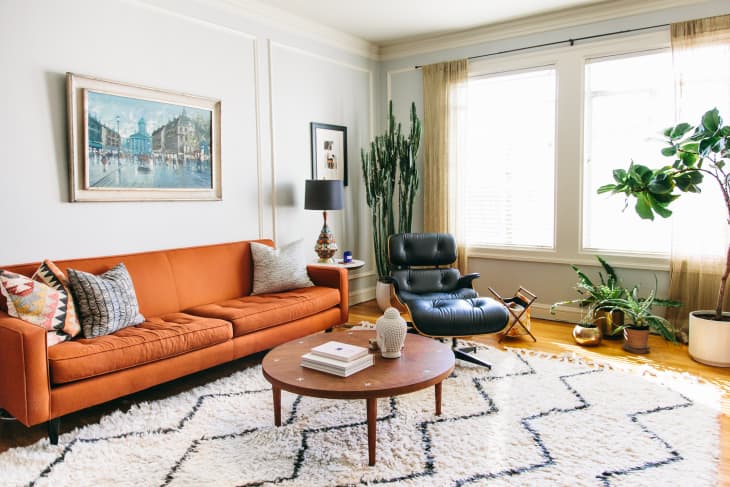 eclectic living room with vintage black tufted chair and burnt orange couch