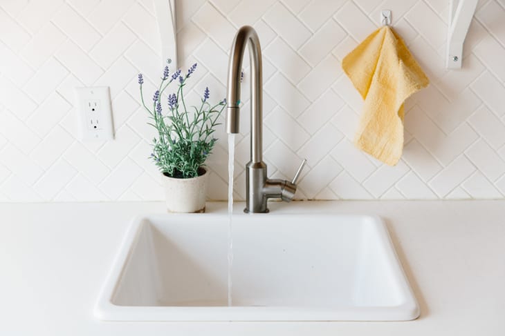 A white sink with a single handle is running