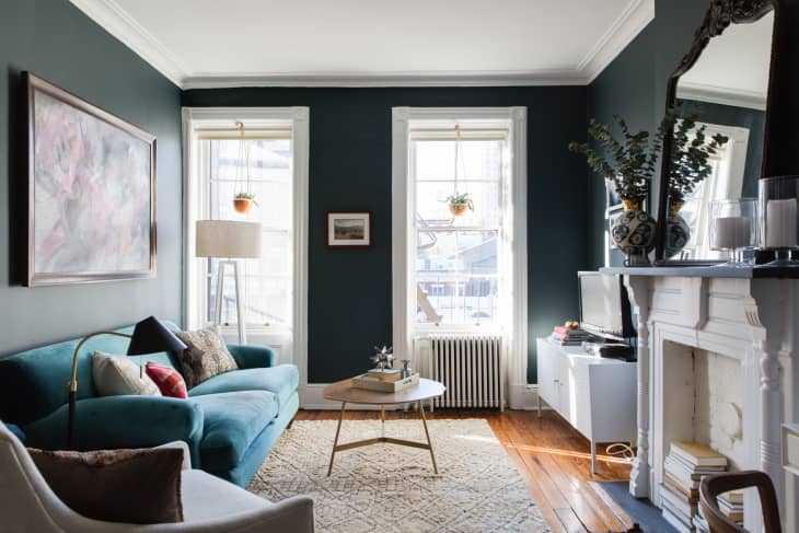 A living room with dark walls and blue couch