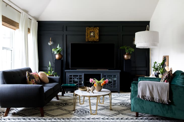 Large bright living room with black accent wall with wainscoting and a mounted tv