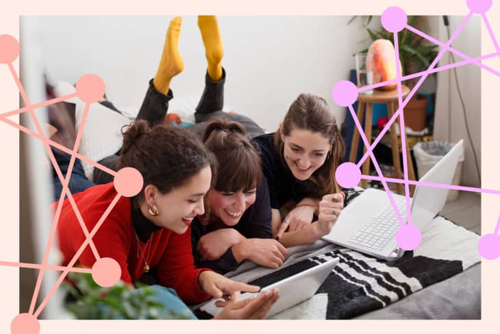 Three people lying on a bed, smiling and looking at a tablet, with a laptop nearby.
