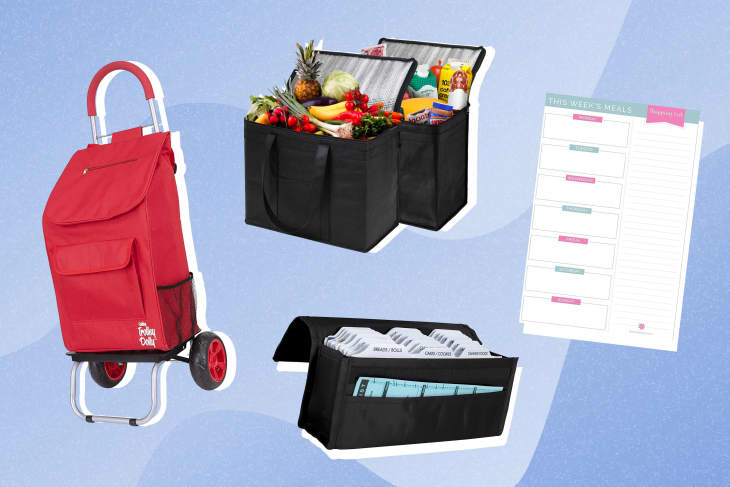 Red shopping trolley, black grocery bags with produce, meal planner, and coupon organizer on blue background.