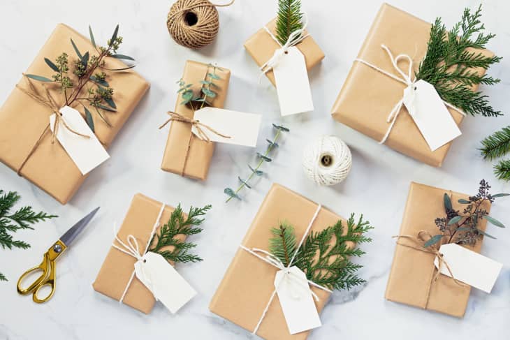 Brown paper-wrapped gifts with twine, greenery, and blank tags, surrounded by scissors and twine spool.