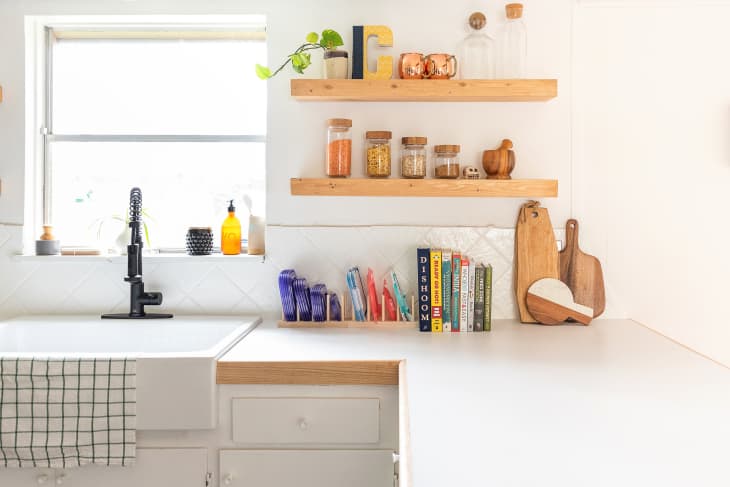 Organized white kitchen with wooden shelving and decor.