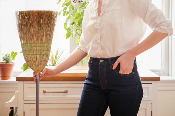 holding dirty broom in kitchen