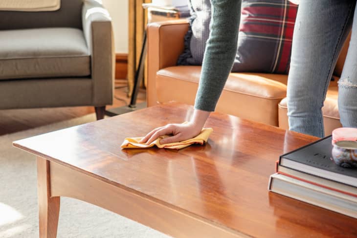 Wiping down coffee table with dusting cloth