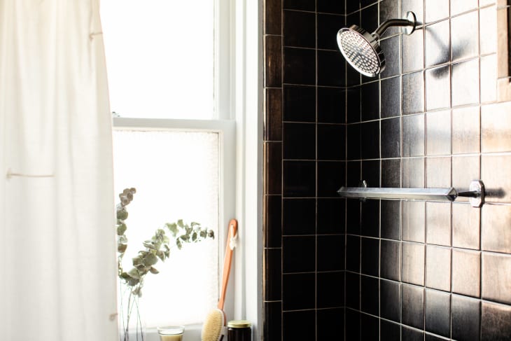 Pretty shower with black tile, white shower curtain pulled aside