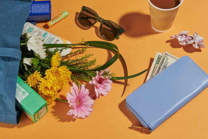 Tote bag with flowers, sunglasses, receipt, wallet and coffee cup on a gold background