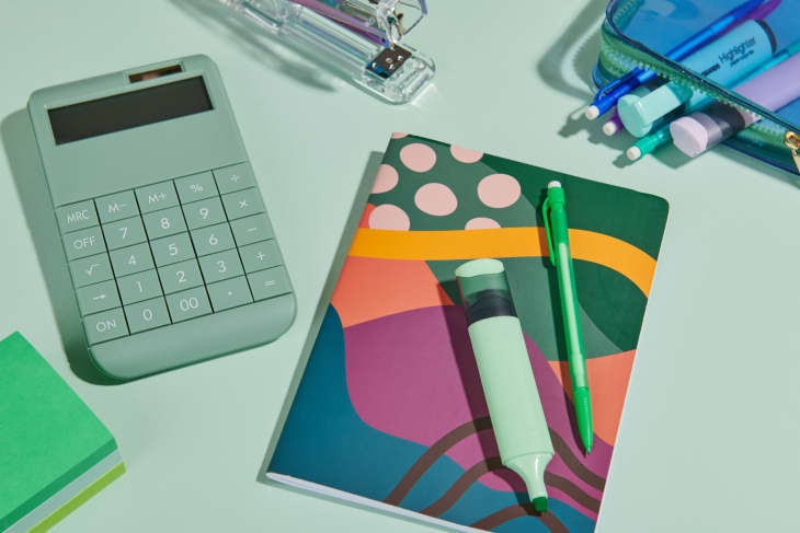 Green calculator, notebook, and office supplies on a green background