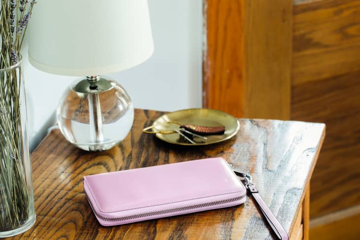 Purple wallet on an entryway table, with keys nearby, lamp, lavender in a vase