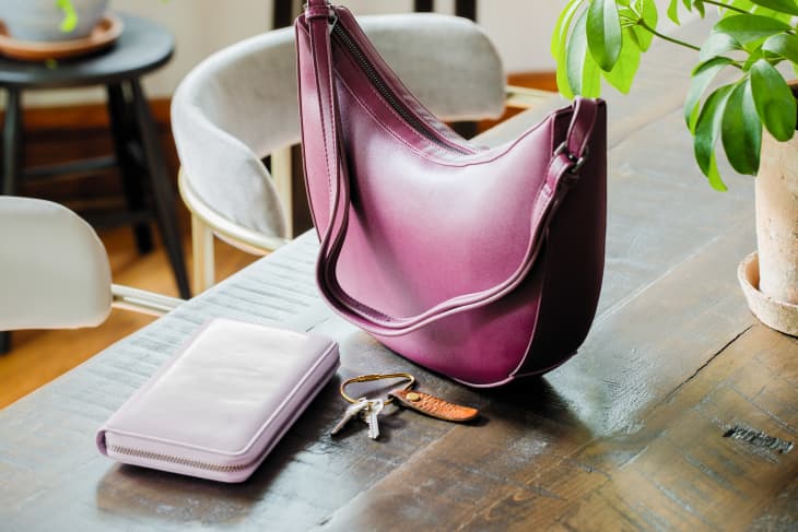 Purple purse, light purple wallet, keys on a dining room table