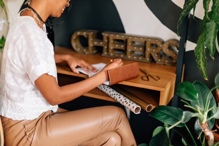 writing a into a notebook at a desk with some present wrapping supplies