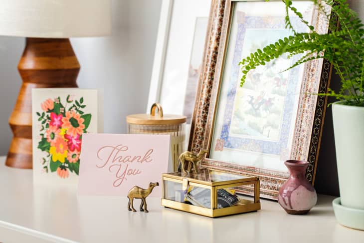 Shelf in someone's home with sentimental objects including greeting cards, small souvenirs, framed art