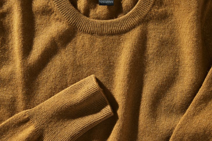 Closeup photo of a brown cashmere sweater. Tag is showing, reading "100% cashmere"