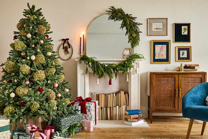 Cozy living room decorated for Christmas with a tree, gifts, a fireplace, and framed art on the wall.