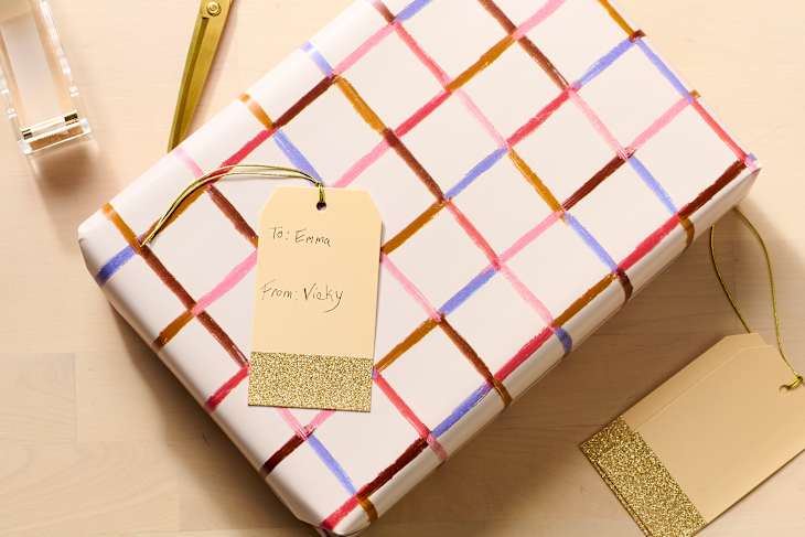 Gift wrapped in white paper with colorful grid patterns, featuring a tag that reads "To: Emma, From: Vicky."