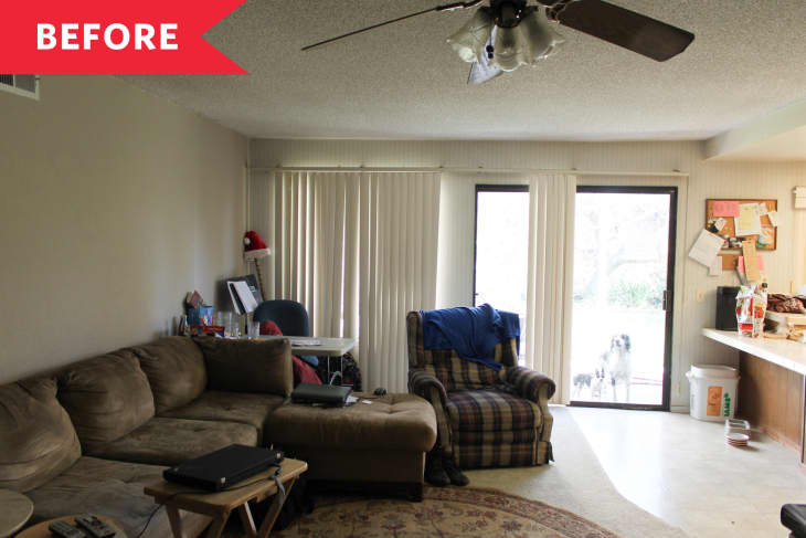 Living room with brown sectional sofa, plaid armchair, sliding glass door, and cluttered desk.