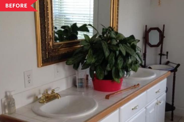 Before: White '90s-style bathroom vanity with wood trim and a brass mirror above