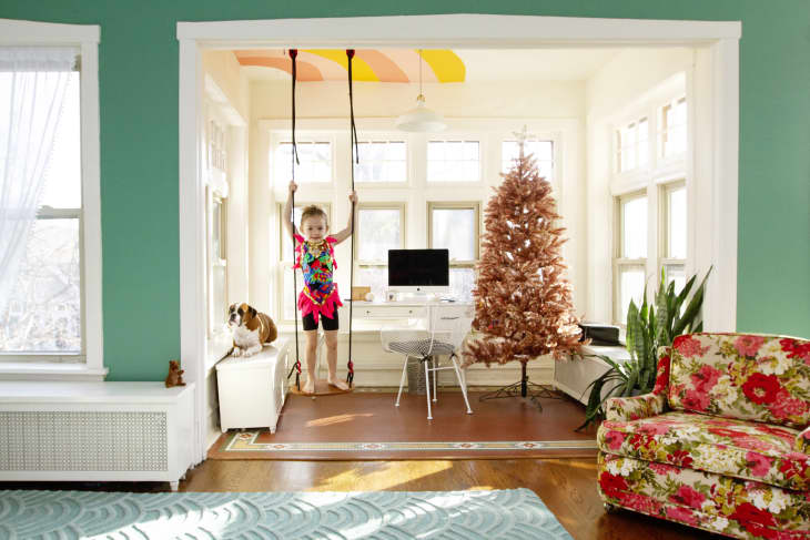young girl on swing hanging from living room ceiling