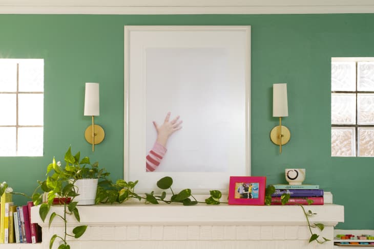 fireplace with green wall and gold sconces hanging above