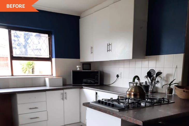 Kitchen with white cabinets, blue walls, gas stove, kettle, microwave, and utensils on the counter.