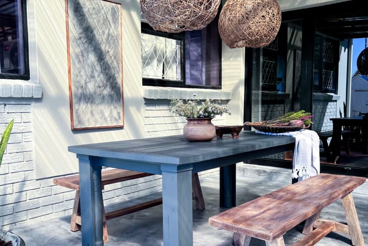 Outdoor patio with dining table, two wood benches, and jute basket-style pendant lights overhead