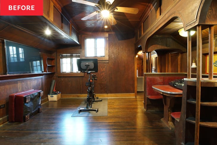 Suite area with built-in dining nook, dark wood wall paneling, and dark wood flooring.