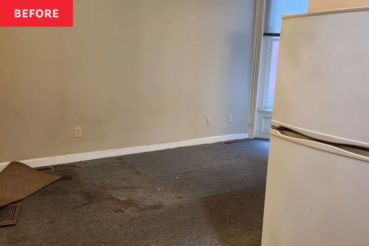 Before photo of studio apartment area that will become the bedroom. Empty room with gray walls, dirty floor