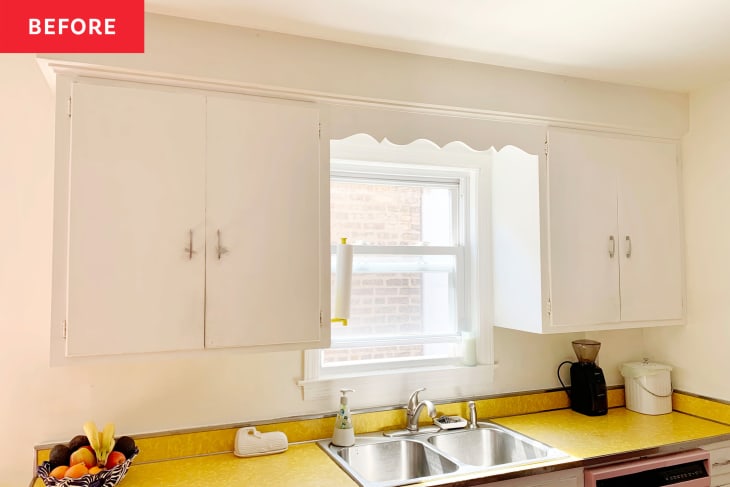 White kitchen cabinets before makeover with metal pulls. Yellow countertop and white trim, window, sink