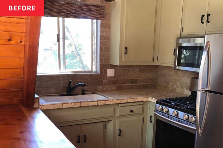 A-frame kitchen before renovation: pale green cabinets with black pulls, brown tile countertops and backsplash/wall, one wood counter.