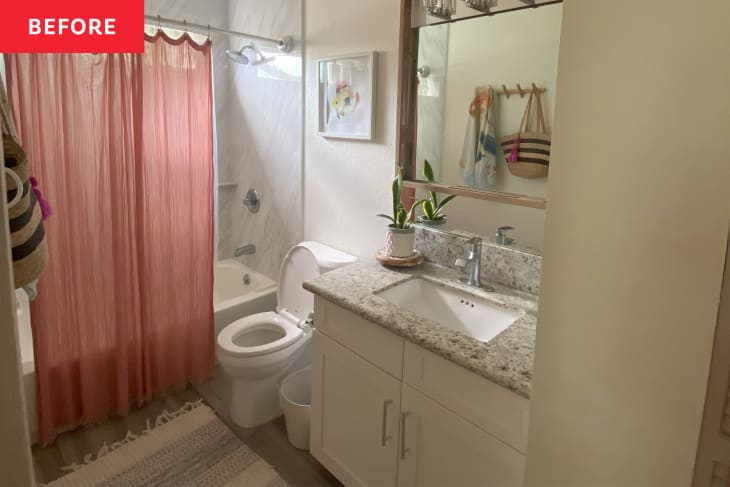 Bathroom with pink shower curtain and light colored vanity before renovation.
