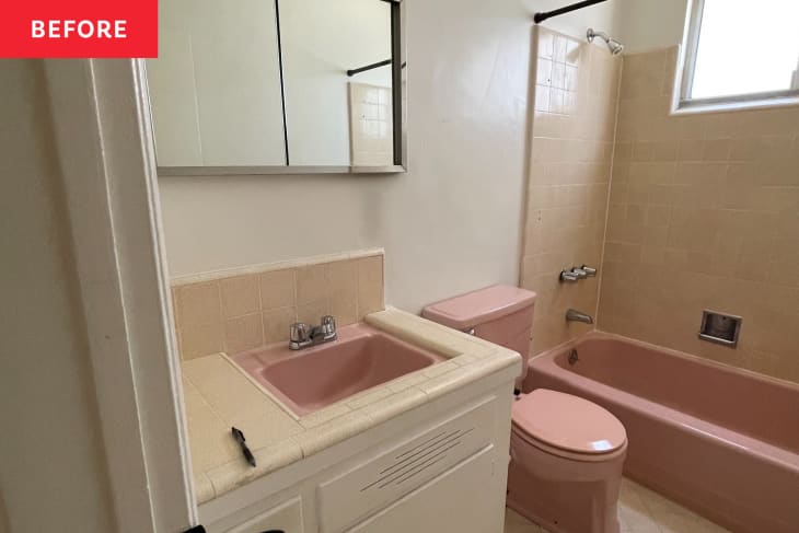 White painted vintage bathroom with pink sink, toilet, and bathtub before renovation. Neutral colored tiles line sink and tub.