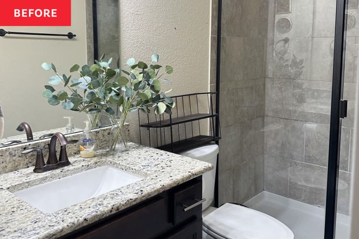Neutral painted bathroom with dark wood vanity topped with speckled beige and grey stone surface before renovation.