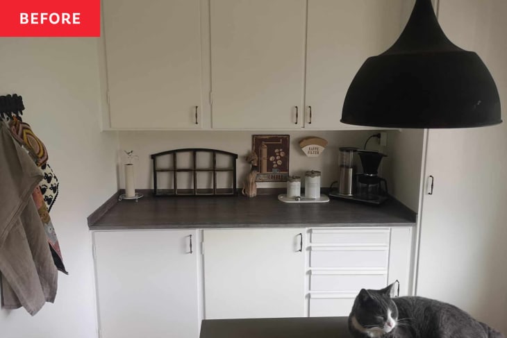 white cabinets, dark countertop, buffet, cat, black hanging light fixture, towel rack on wall, decorative window, coffee maker, knickknacks, pantry