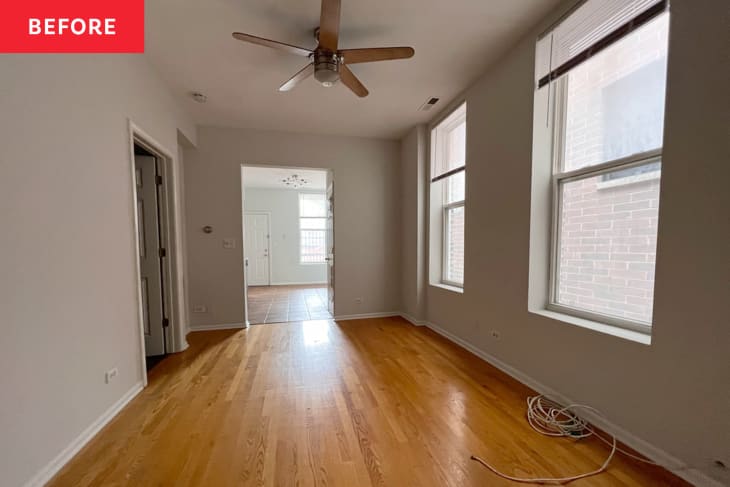 Empty living room with gray walls, wood flooring, and ceiling fan.