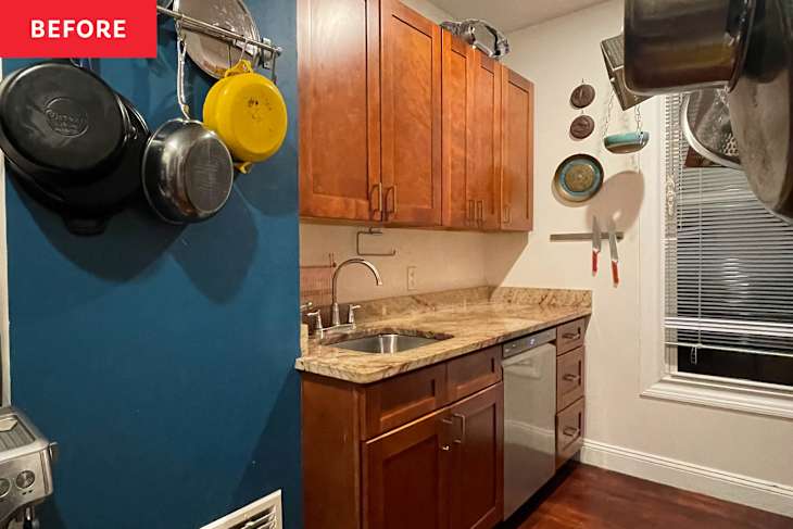 Small kitchen with wooden cabinets, granite countertop, sink, and hanging pots on a blue wall.