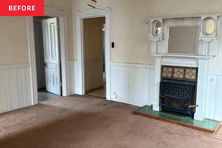 Empty room with brown carpet, white wainscoting, a decorative fireplace, and two doorways leading to other rooms.