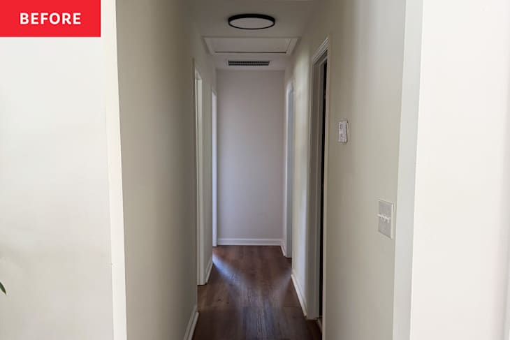 Narrow hallway with light wood flooring, white walls, and doors on both sides leading to rooms.