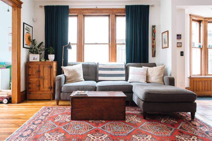 A Persian rug adds accent to the living room furnished with a grey sectional sofa and a wooden coffee table