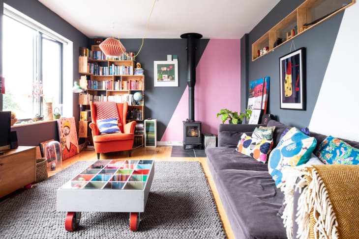 A colorful maximalist living room with an orange wingback chair and full bookshelves in the corner of the room.